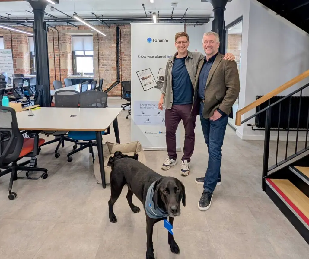 Two men standing in front of a banner with a dog in the front