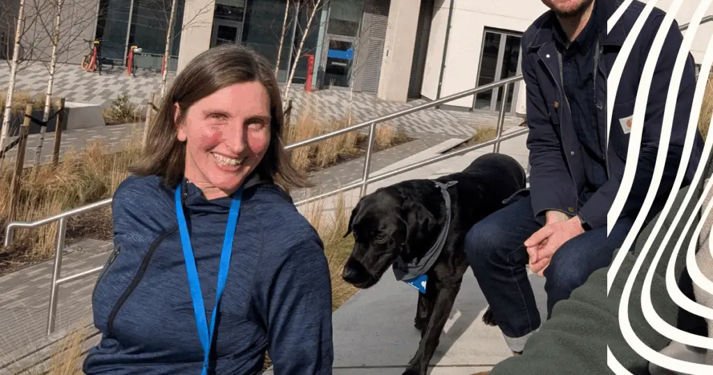 Smiling lady beside black dog